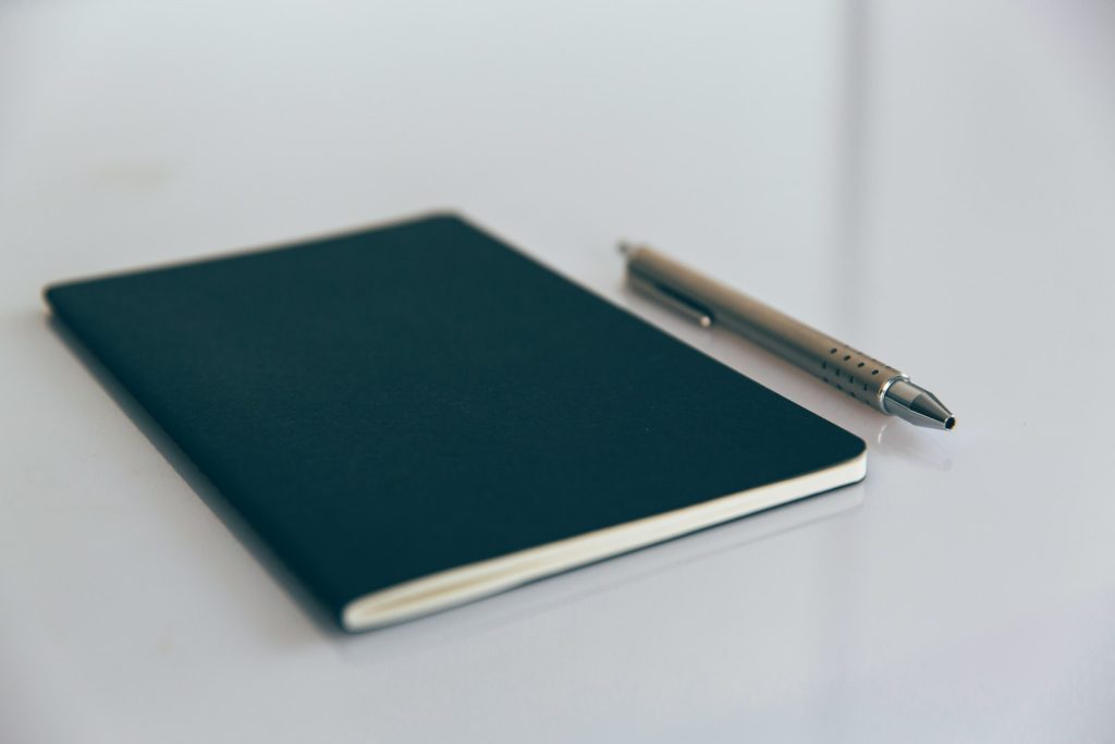 Blue notebook beside a white pen on a desk