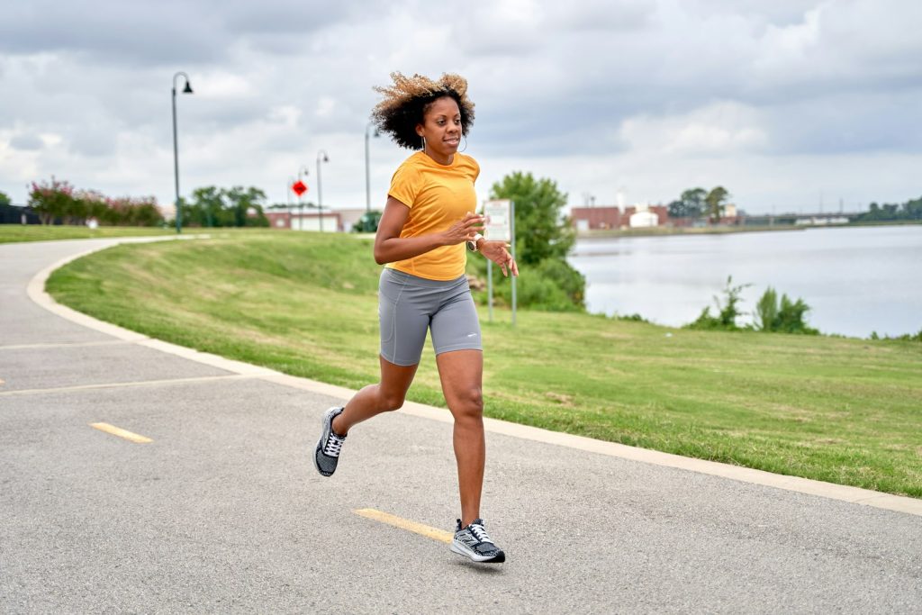 Woman running down a road beside a lake