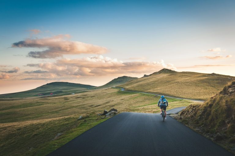 Cyclist on a countryside road with mountains behind