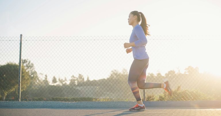 Woman jogging near a wire fence