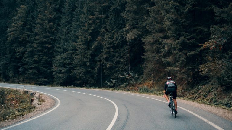 Cyclist riding a road bike on a winding forest road