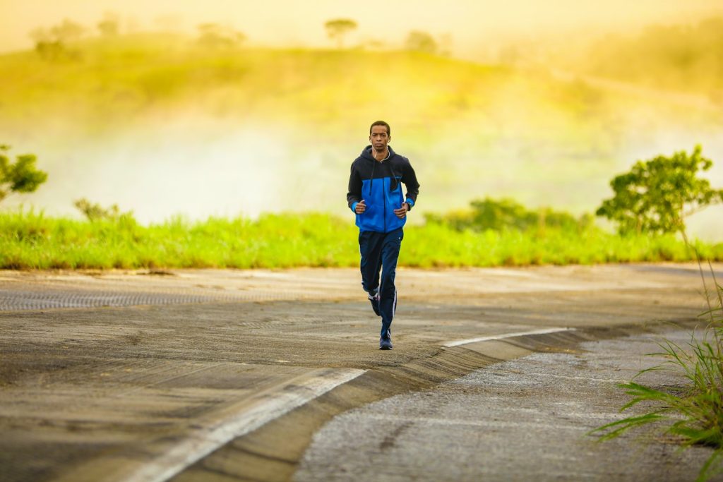 Man in a track suit jogging along a road