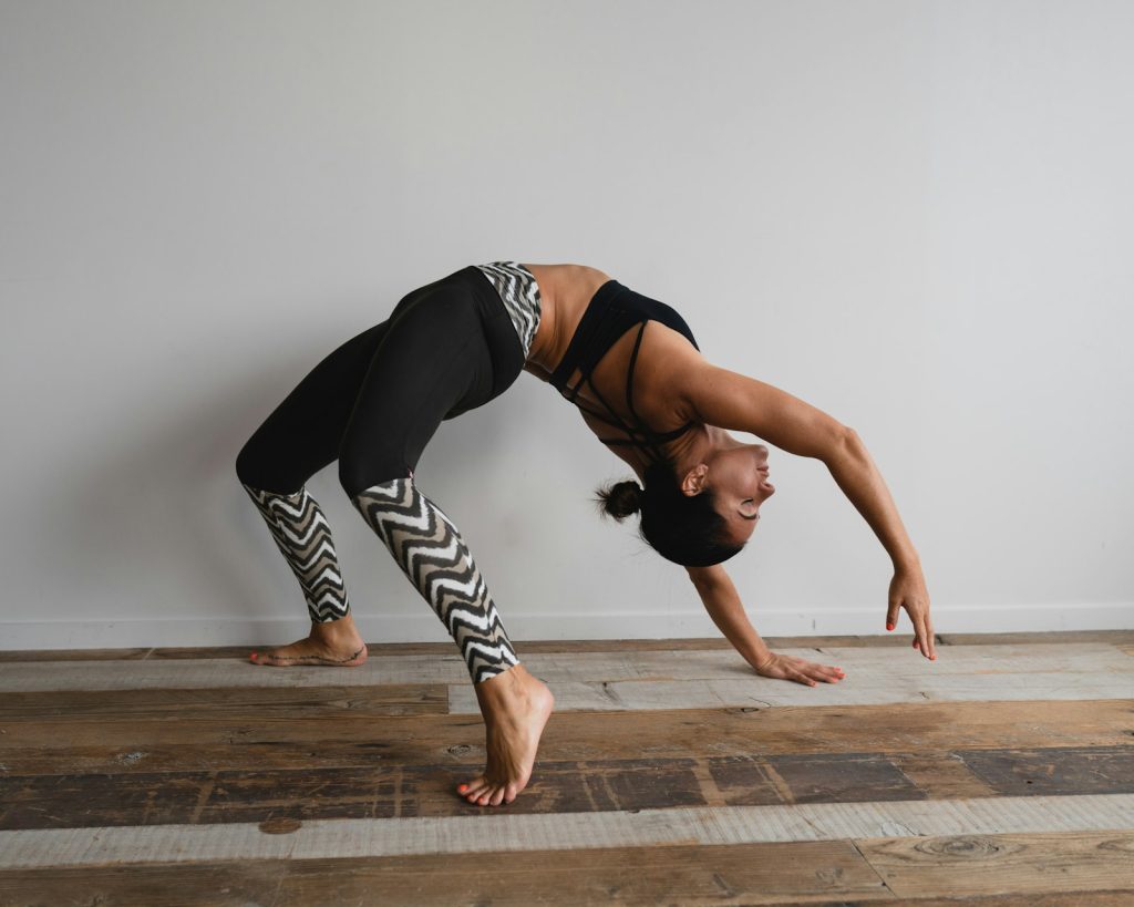 Woman in a backbend yoga pose beside a wall