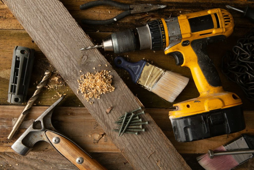 Hammer and cordless drill resting on a wooden table
