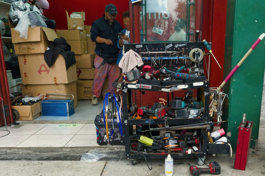 Man working at a cluttered tool cart outside a shop
