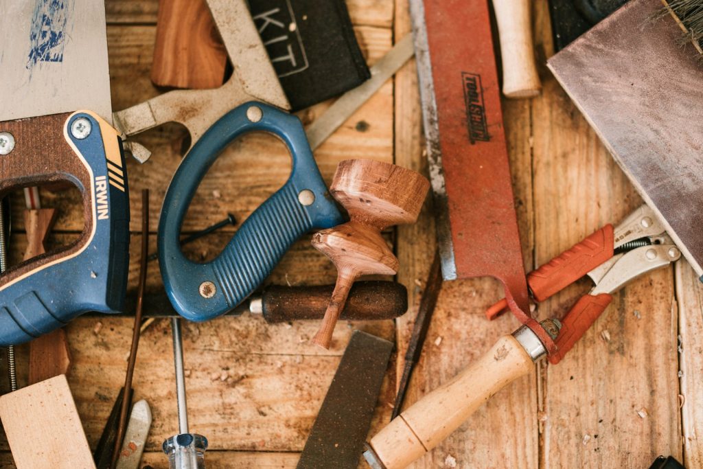 Pliers beside a wooden-handled tool