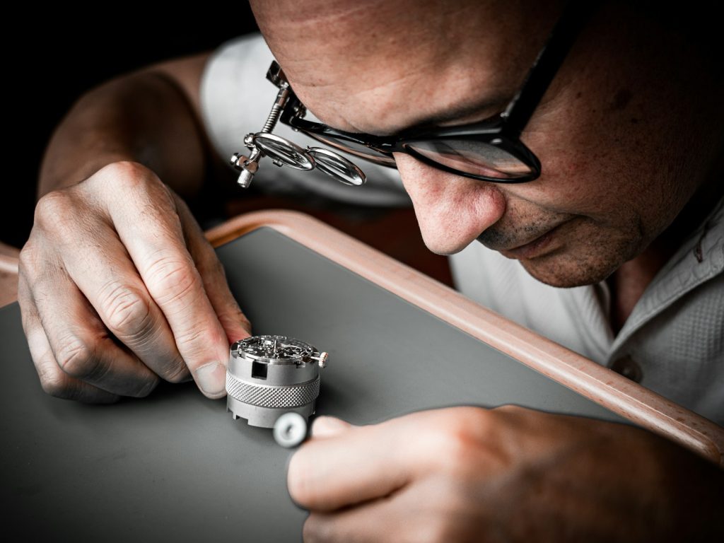 Watchmaker with loupe examining a mechanical movement