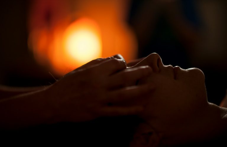 Hands giving a facial massage in warm light
