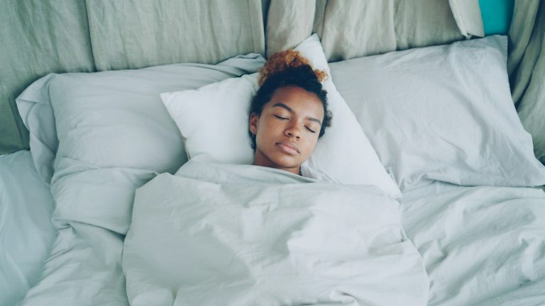 Young woman sleeping peacefully in white bed