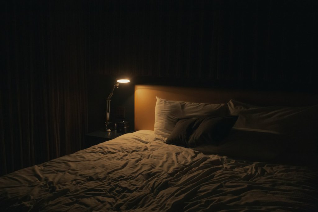 Lit table lamp beside a bed