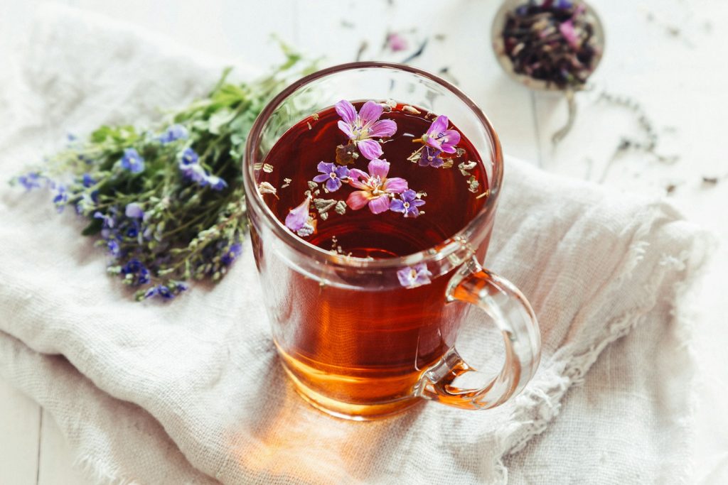 Herbal tea with blossoms in a glass mug