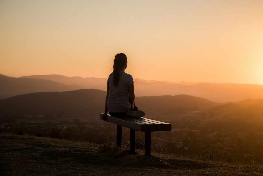 Woman sitting on bench overlooking mountains